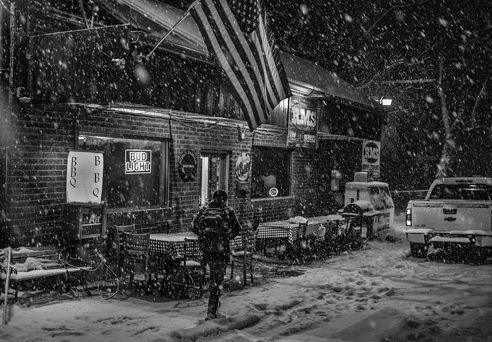 A man walks by a restaurant in an East Nashville neighborhood during the February snowstorm of 2021.