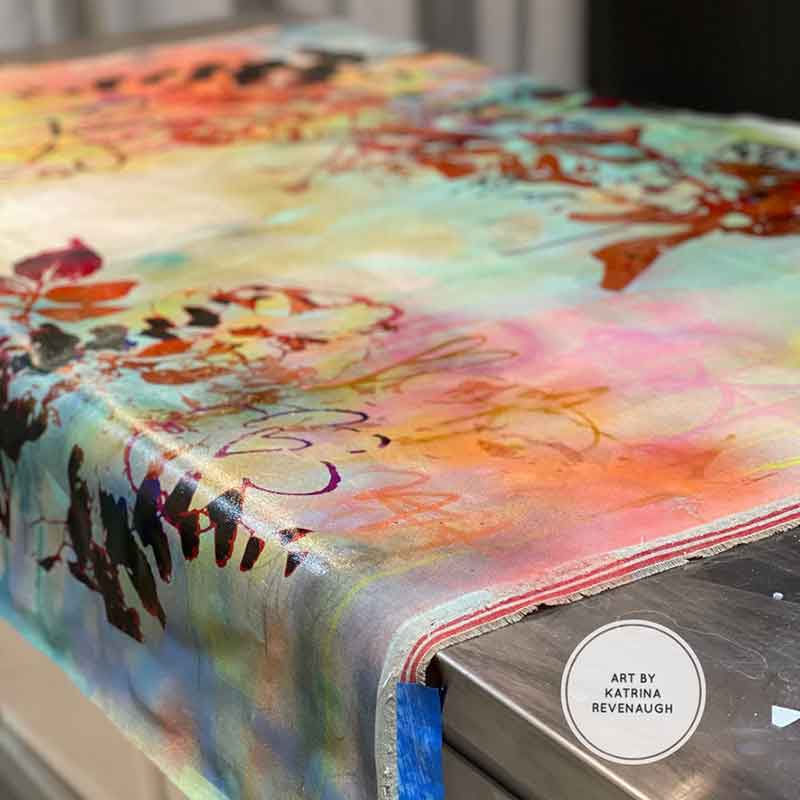 A fresh canvas painting by Katrina Revenaugh in her workspace on a table.