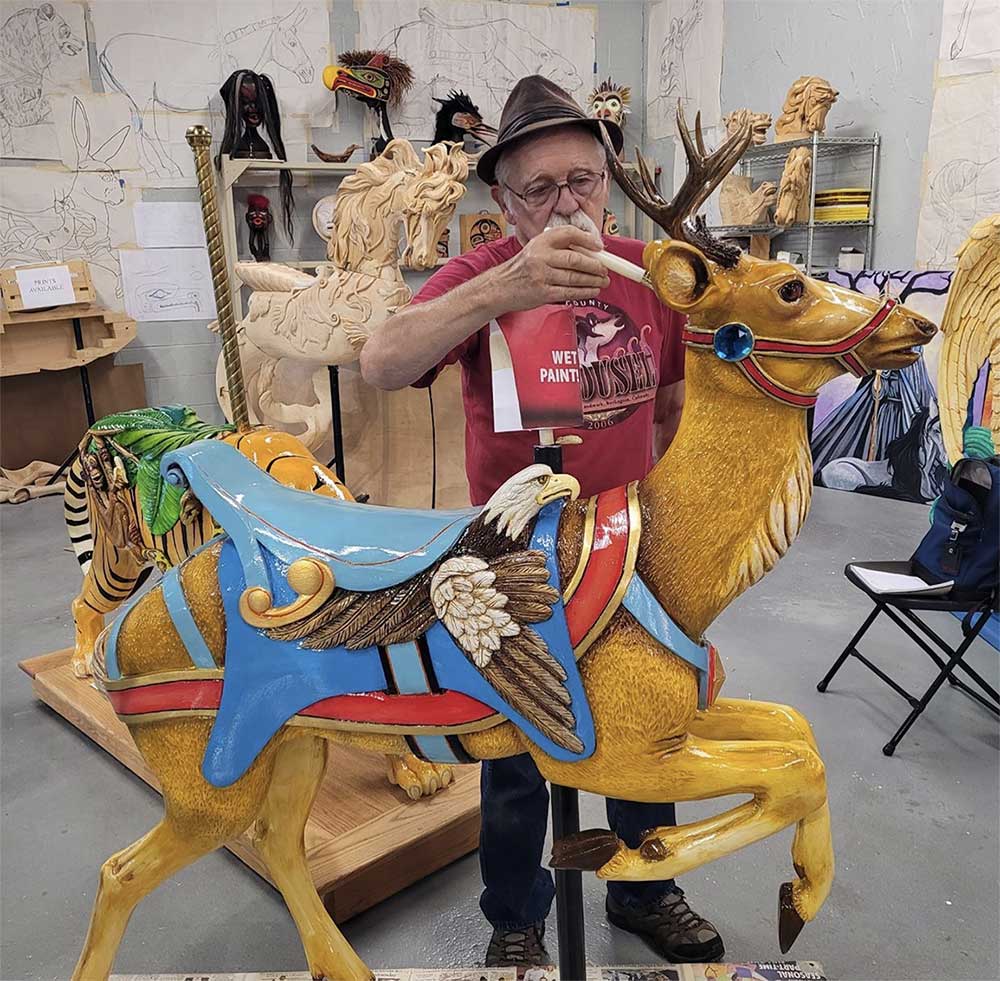 Artist completes final touches carved wooden carousel deer