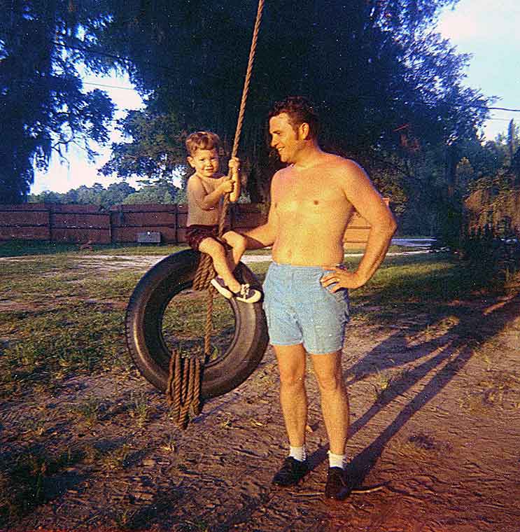 Boy on tire swing with dad.