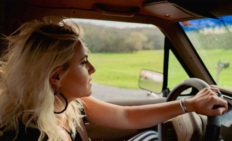 Singer-songwriter Emma Zinck driving in a car redefining Nashville Country.